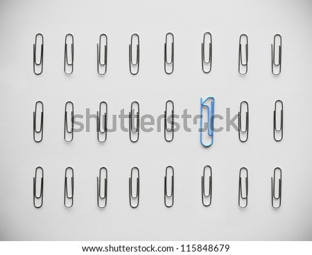 One versus zeroes. Standing out from the rest. Unique paperclip shaped as number 1 stands out in a crowd of regular paperclips shaped like zeroes.