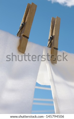 Fluffy soft white laundry is drying outside on clothesline with bright blue skies and fluffy white clouds. So clean!