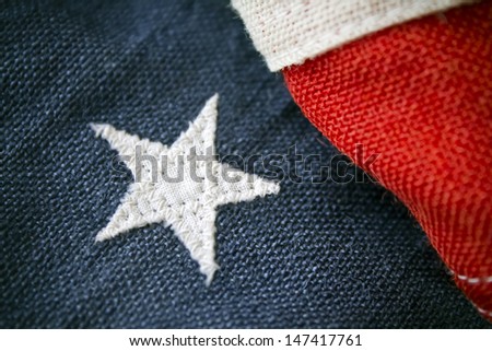 A close up of an antique American flag with a single proud white star on blue with red and white stripes, highly textured