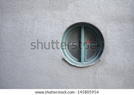 Round window on a blank grey wall
