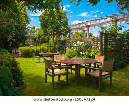 Landscaped Garden With Wooden Dining Table Set In The Shade Of Trees