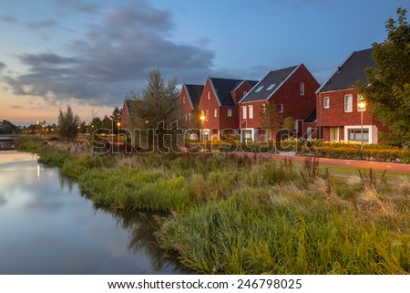 Long exposure night image of a suburban Street with modern ecological middle class family houses with eco friendly river bank in Veenendaal city, Netherlands.