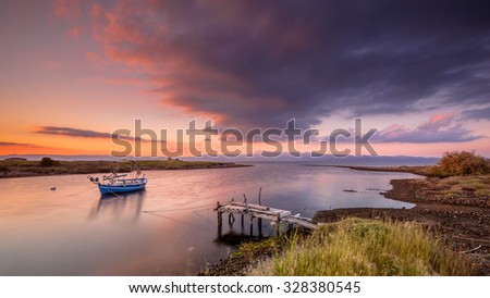 Fishing boat in a river mouth bay during a purple sunrise on Lesbos island, Greece