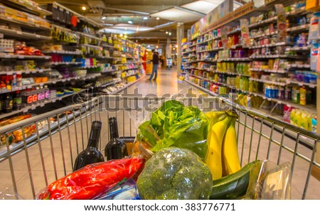 Supermarket trolley at an  aisle filled up with healthy vegetables seen from the consumers point of view from above
