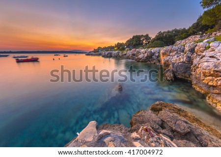 Colorful sunset over the rocky coast of Croatia. Long exposure image of sunset, rocks, boats and turqoise water on the Island of Cres.