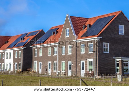 Modern row houses with solar panels, brown bricks and red roof tiles in neoclassical style in Groningen Netherlands on sunny day