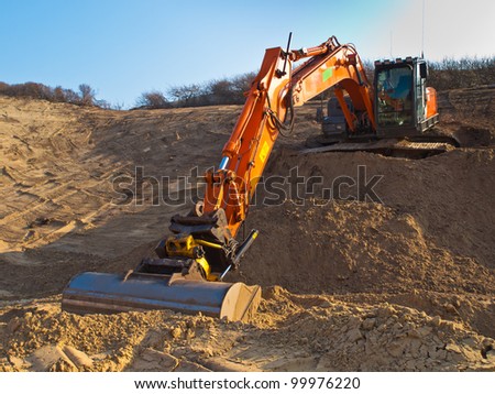 Heavy orange excavator at work in a sandpit seen from the front