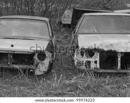 A car graveyard with old and rusted car wrecks in black and white