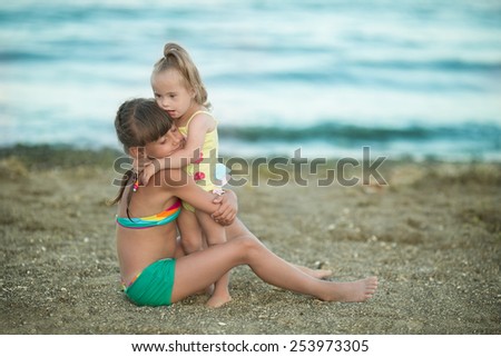beautiful girl playing with her younger sister with Down syndrome on the beach