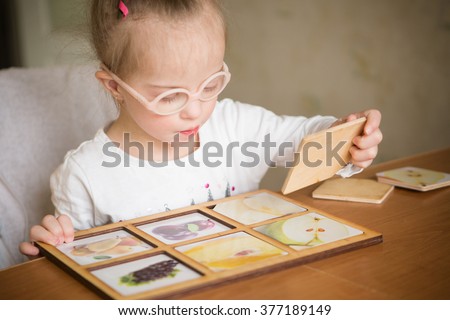 smart girl with Down syndrome collects puzzles