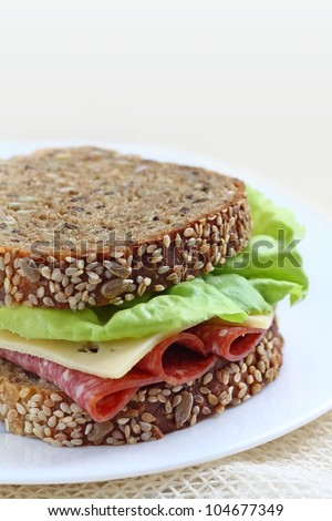 Sandwich made of healthy brown bread with seeds  lettuce italian salami and cheese