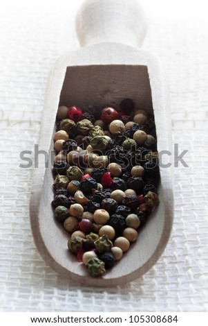 Close up of assorted peppercorns on measure wooden spoon