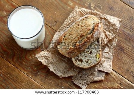 Top view on cut in halves whole grain bread roll and a glass of milk