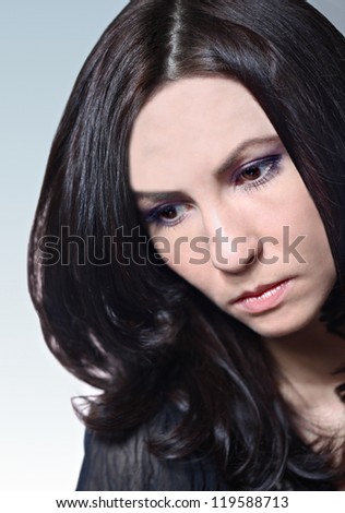 Young Caucasian woman with dark long hair looking sad