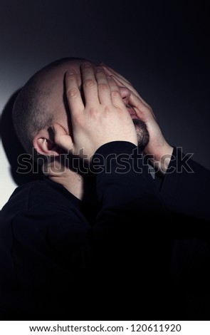 Close up of a Caucasian man covering face with hands from desperation