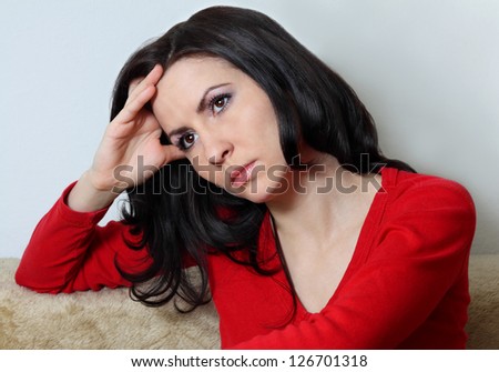 Young good looking brunette with long hair sitting supporting her head with hand