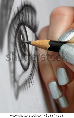 Close up of woman hand drawing an eye with graphite pencil