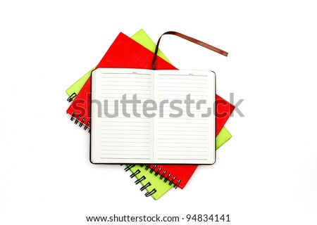 Top view of open diary on the top of two spiral-bound red and green notebooks isolated on white background