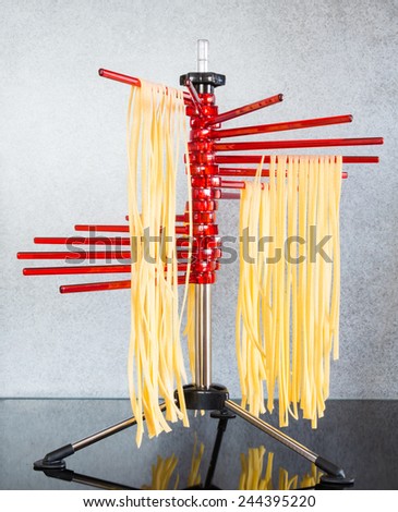 Self-made italian tagliatelle hanging on a pasta drying rack.