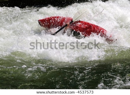 Red kayak turning over in the whitewater.