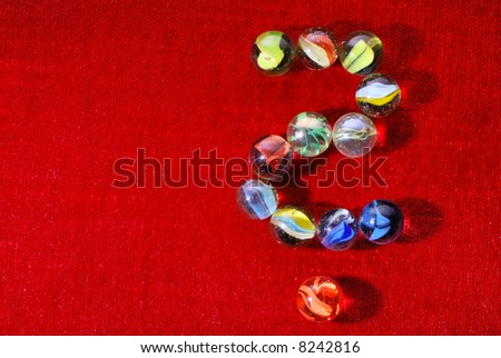 question mark of glass marbles on red velvet