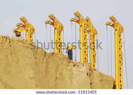 Construction site with drilling rigs behind a sand hill.