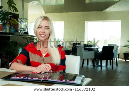 blonde girl makes a choice from the menu in the cafe