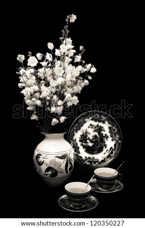 vase of flowers and two cups of tea on a dark background