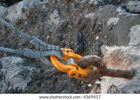 An orange link connecting cables to a hold in the rock