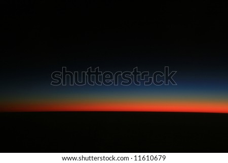 Cool red and blue sunset light fading into a black sky and earth