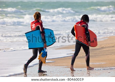 SAN FERNANDO, CADIZ, SPAIN - FEB 19: Unknown bodyboaders leaving the water on the 2nd championship of Surf and BodyBoard Impoxibol on Feb 19,2011 on the beach of San Fernando, Cadiz, Spain
