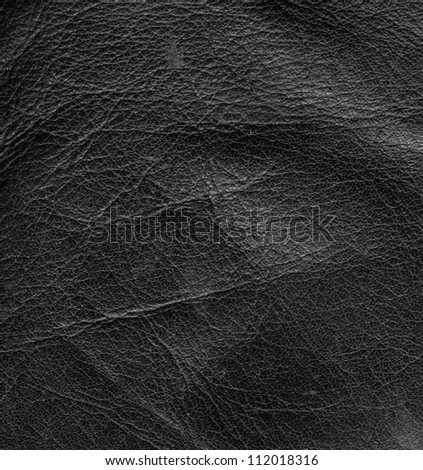 full frame abstract background showing a old black rippled leather surface