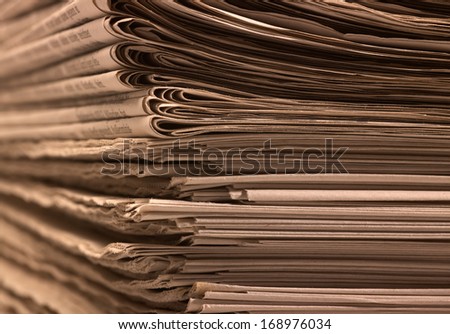 full frame background with lots of stacked newspapers, brown toned