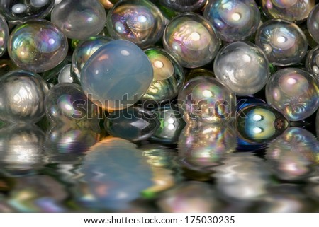partly sunken iridescent glass beads on reflective water surface