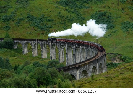 the Glenfinnan Viaduct in Scotland with the Jacobite steam train driving over it, in green overgrown ambiance