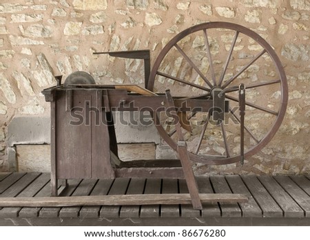 historic grinding wheel on wooden ground in front of a stone wall