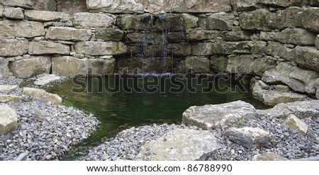 small pond surrounded by a stone wall with flowing water