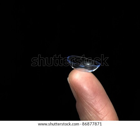 optical theme showing the studio photography of a soft contact lens placed on a finger tip in black back