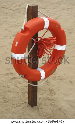white-striped red life belt hanging on a stack at the beach