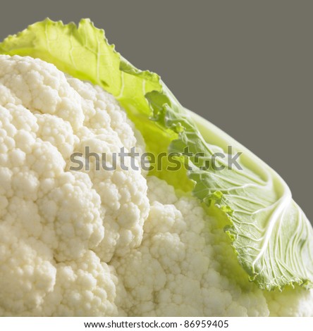 detail studio shot of a cauliflower and leaf in grey back
