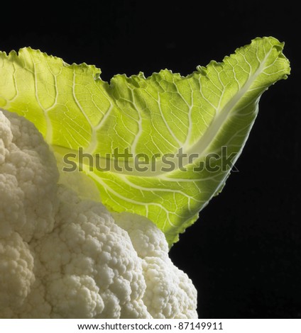 detail studio shot of a cauliflower and leaf in black back