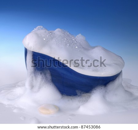 symbolic cleaning and washing background with bathtub,soap and lots of foam in blue gradient back
