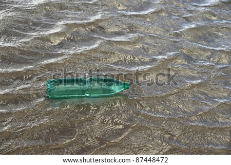 pollution theme with a green plastic bottle floating on water surface