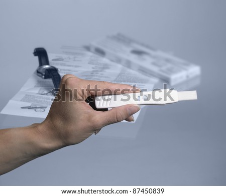 pregnancy test with hand and wristwatch in grey back