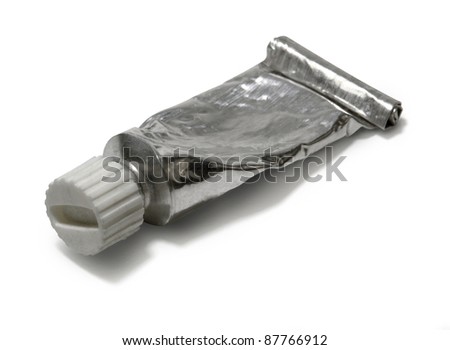 studio photography of a closed old metallic paint tube reclined with shadow and clipping path