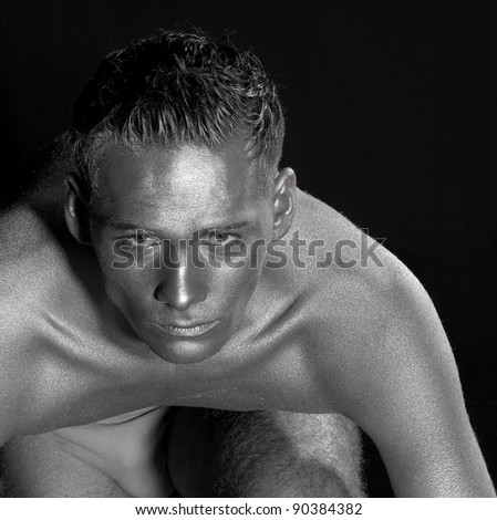 silver bodypainted portrait of a concentrated young man.Studio shot in black back