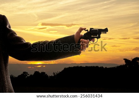 silhoutte of a man with a handgun at sunset