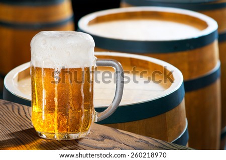 glass of beer with old wooden barrels