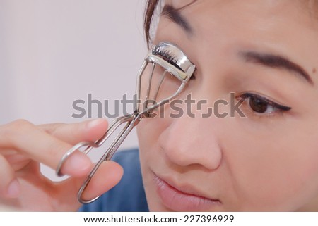 Beauty portrait of young asia woman using eyelash curler