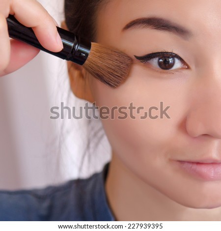 Young beautiful Asia woman applying her make-up brush on.